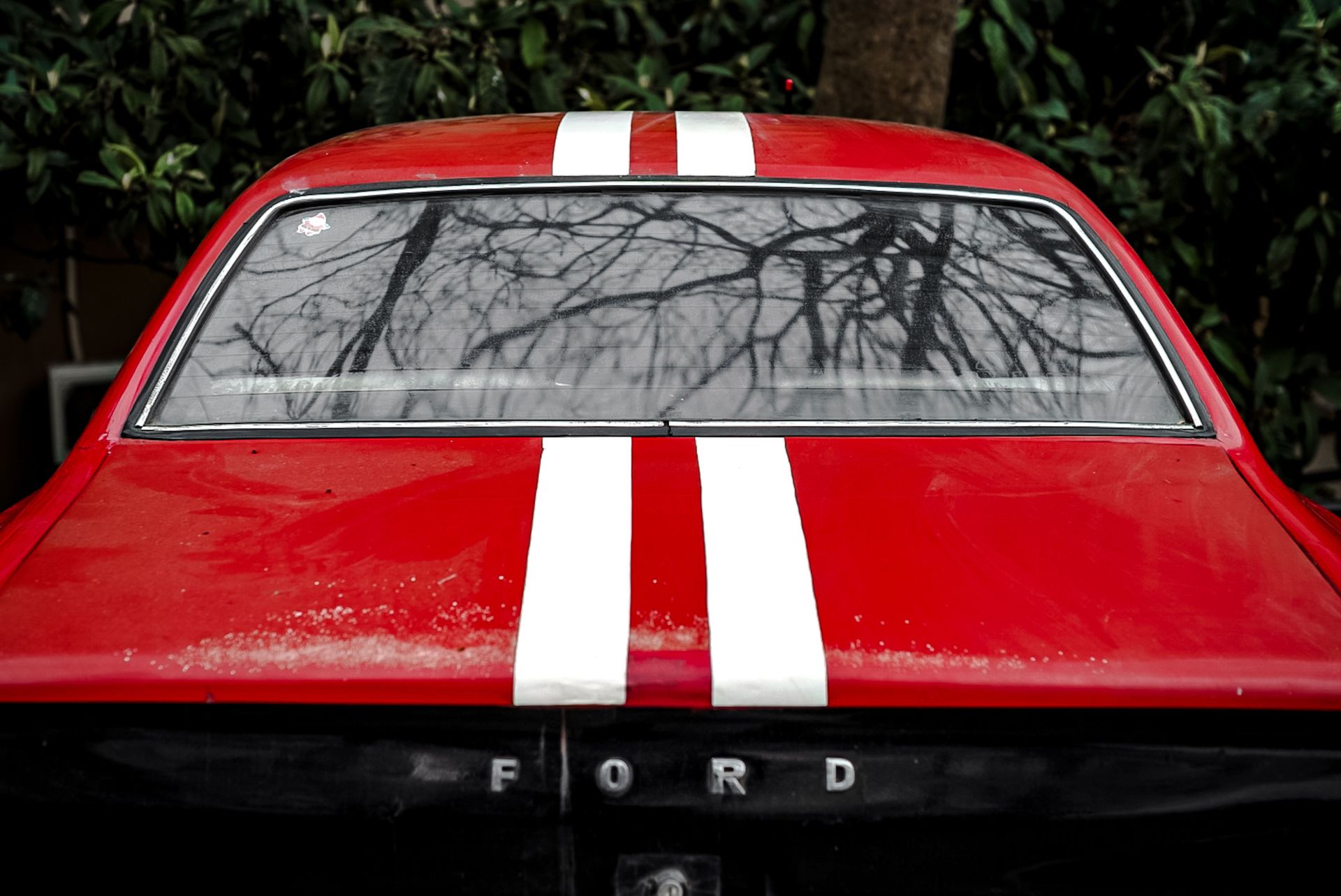 Close-up of a red vintage Ford Mustang featuring white racing stripes and a classic design.